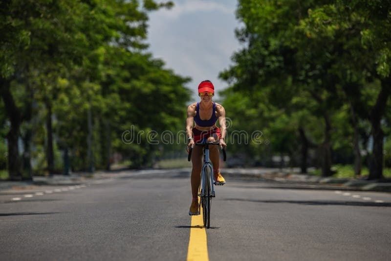 Fietser rijdt rustig over een rechte, zonnige weg met bomen