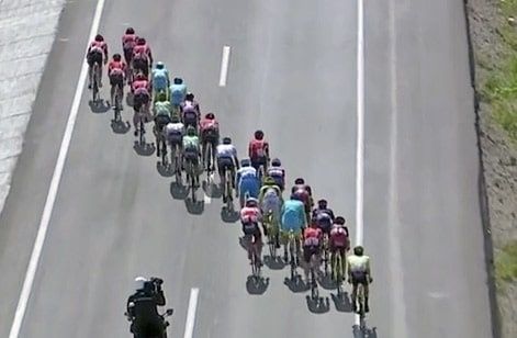 Wielrenners rijden in een lange waaier over een open weg