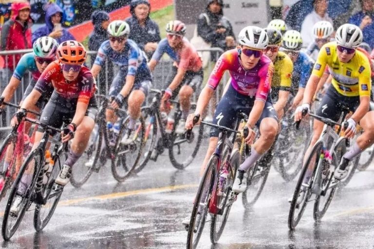 Vrouwenpeloton rijdt in zware regen over een natte weg