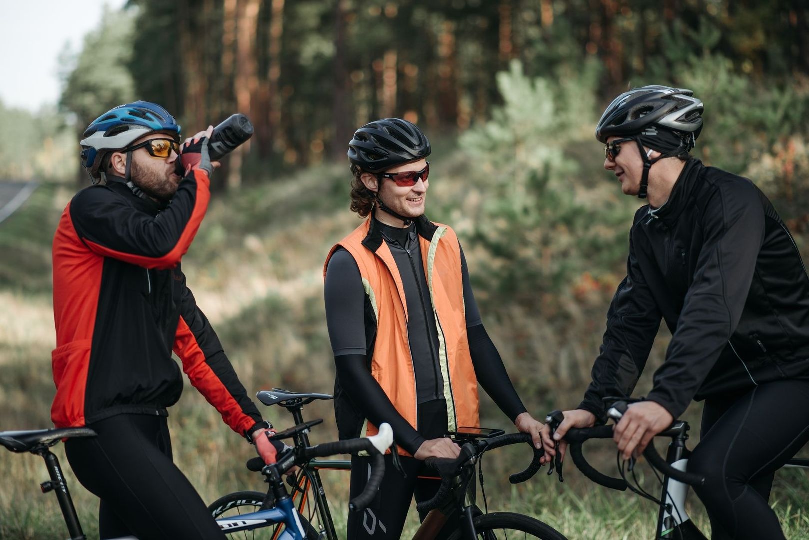 Drie fietsers in het bos, van wie één uit een bidon drinkt
