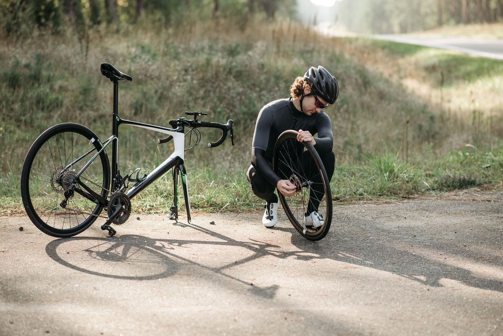 Fietser controleert een racefietsband langs de weg